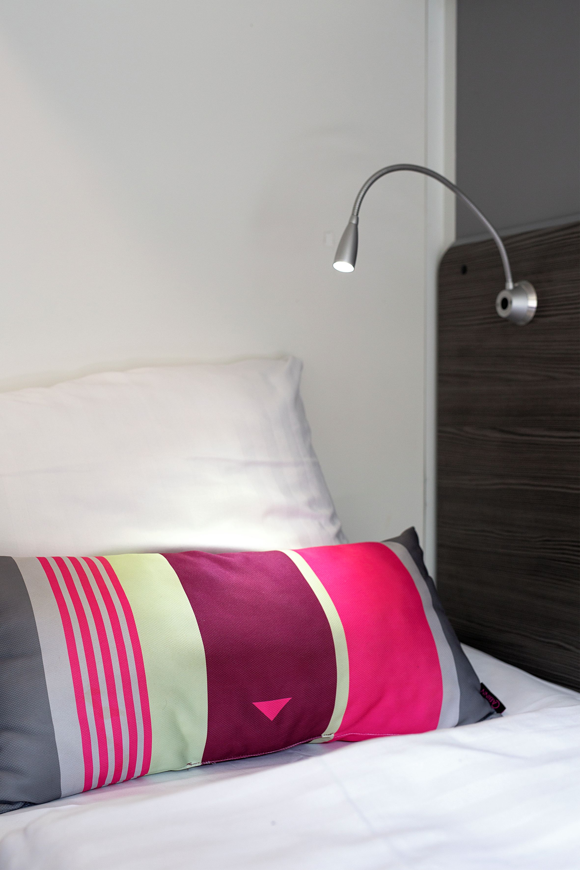 A bed with a pillow and a bedside lamp.