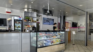 A modern reception area with a refrigerated display case, a digital kiosk, and a reception desk.