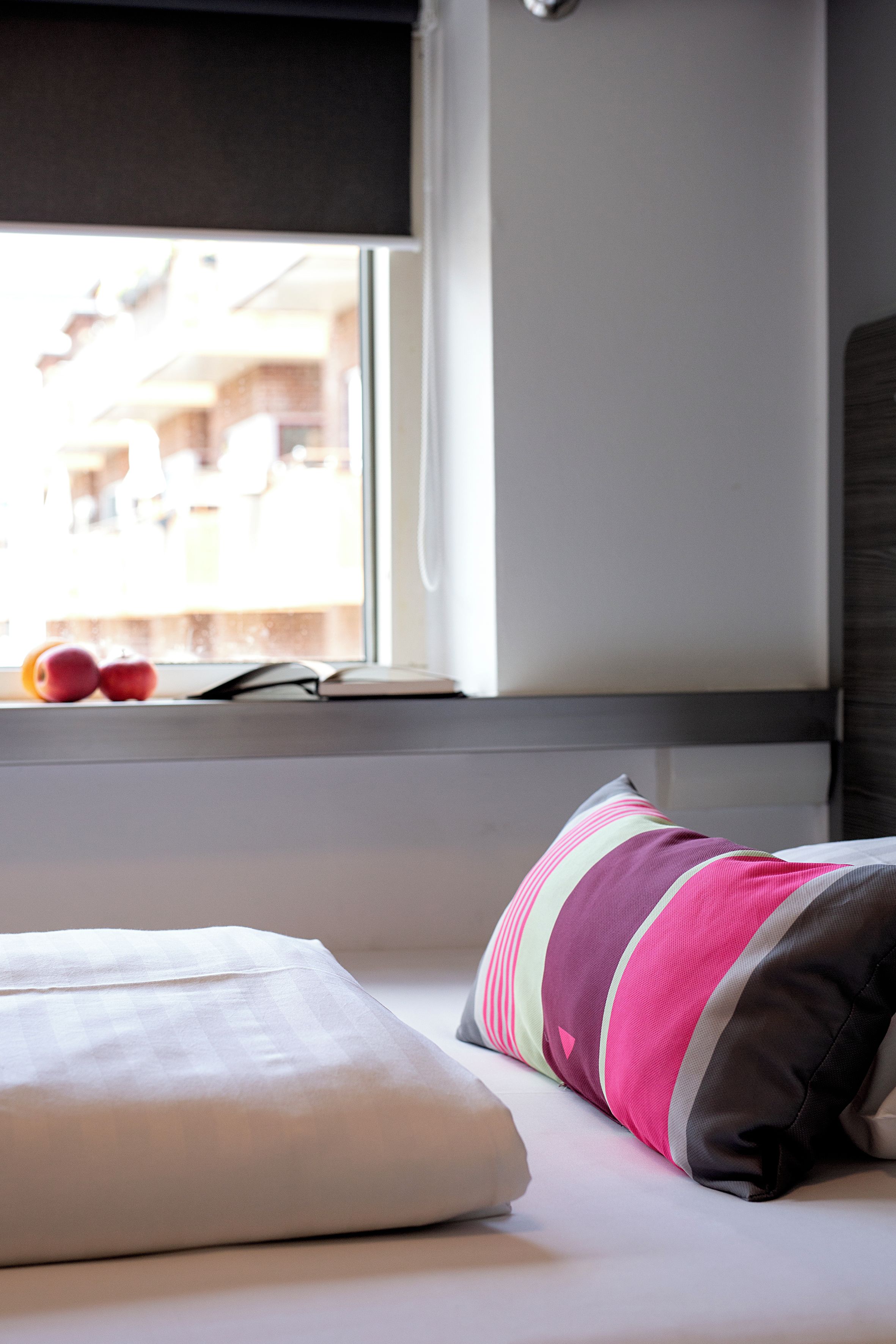 A bed with pillows and a window with a view of the outside.