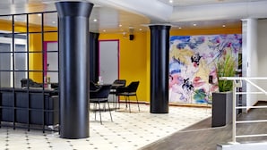 A modern interior with a dining area, black chairs, a white table, and a colorful abstract mural on the wall.