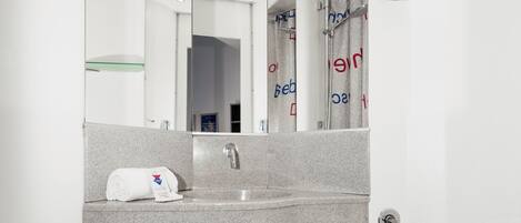 A modern bathroom with a large mirror, a sink, a toilet, and a glass shelf.