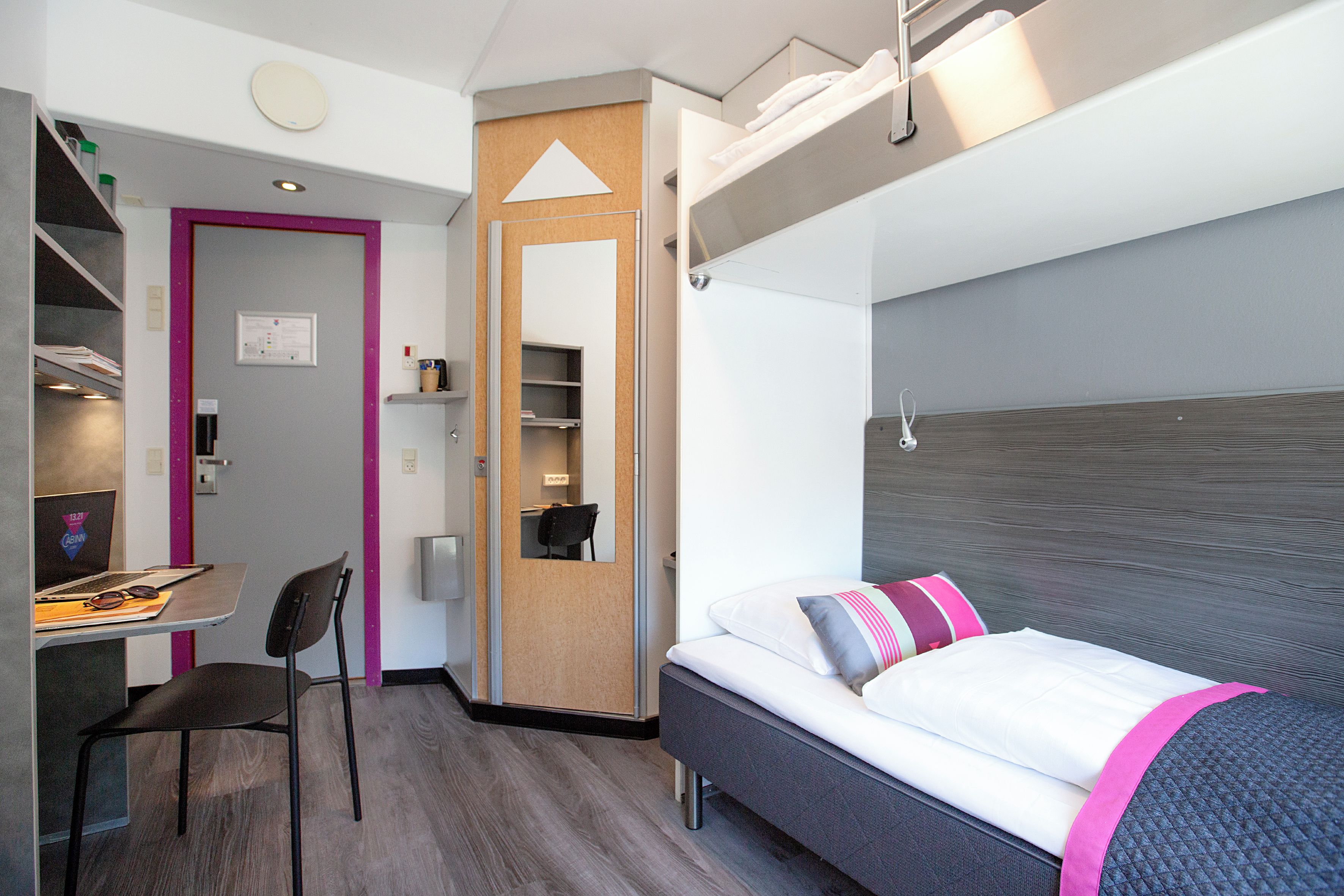 Habitación de hotel pequeña con cama, escritorio y silla.