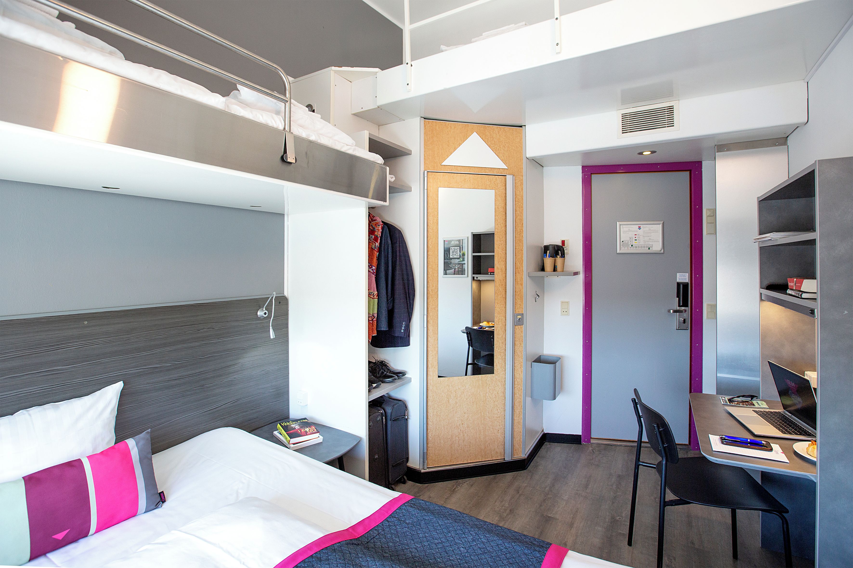 Une chambre d’hôtel comprenant un lit, un bureau, une chaise, une armoire et une salle de bain.
