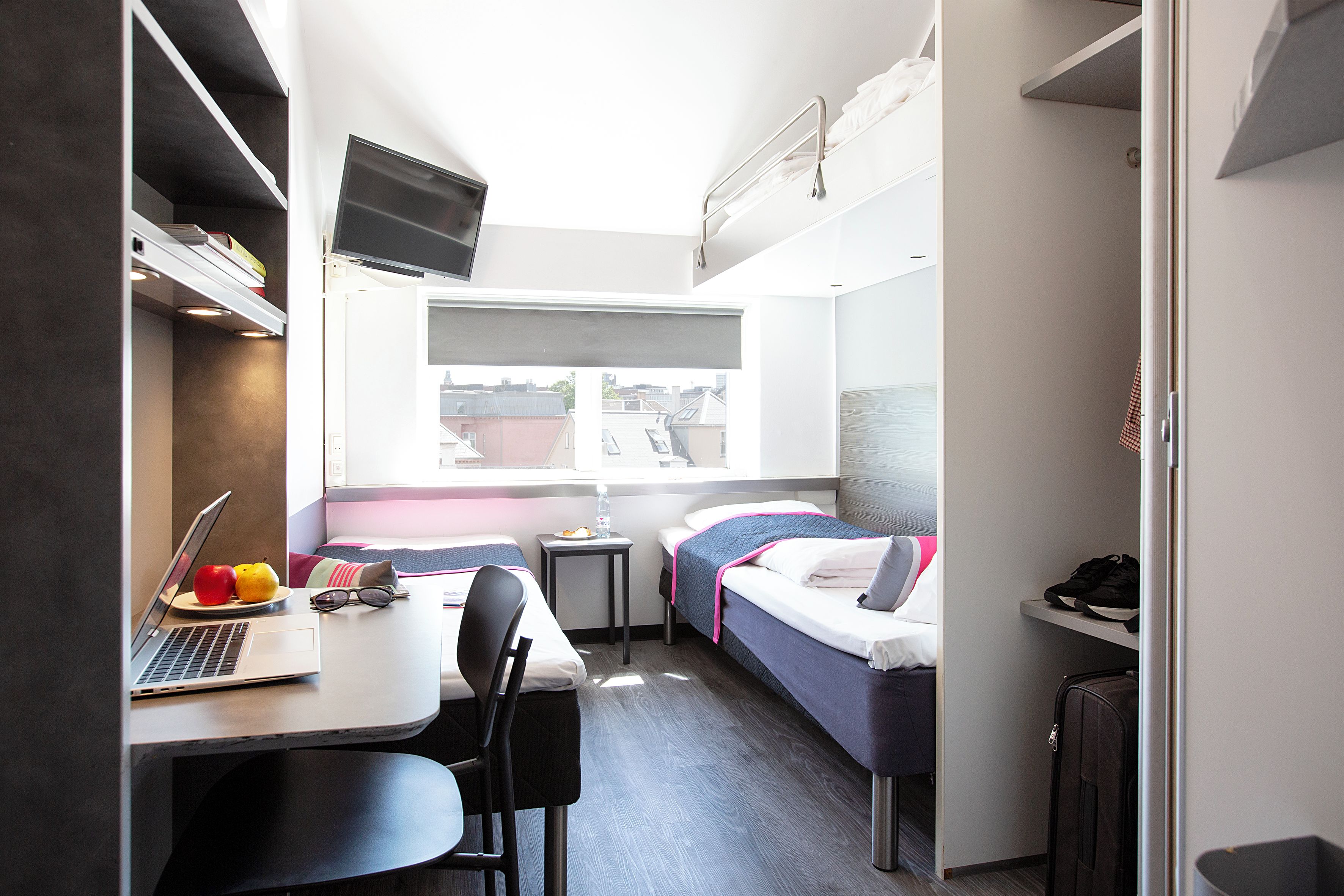A compact room with a bed, a desk with a laptop, and a chair.