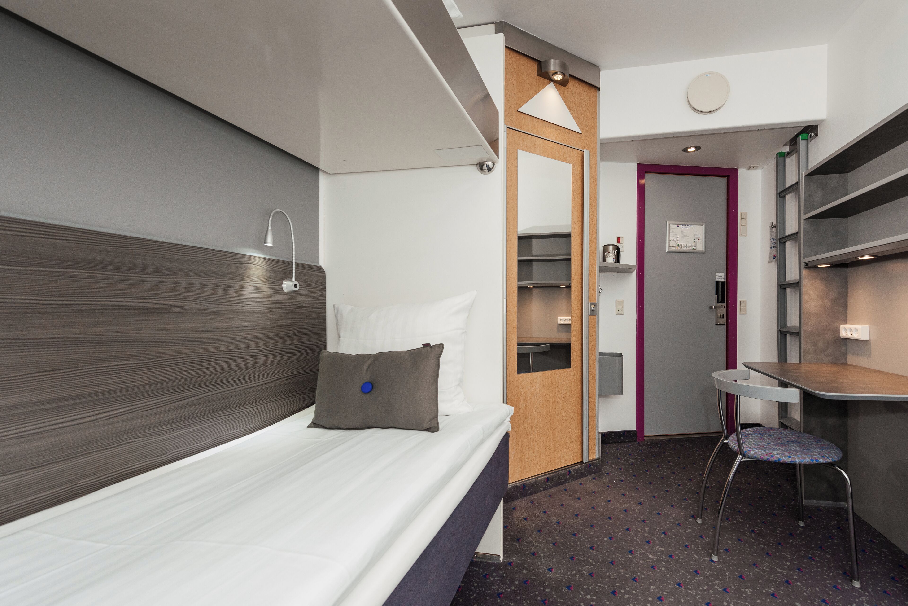 Una habitación de hotel moderna con cama, escritorio y silla.