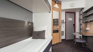 Et moderne hotelværelse med seng, skrivebord og stol.