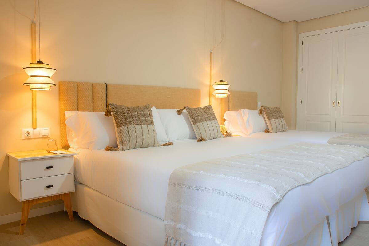 A hotel room with a large bed, two bedside tables, and two wall-mounted lamps.
