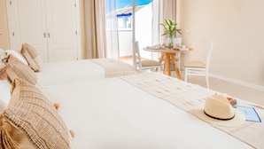 Hotellihuone, jossa on suuri sänky, pieni pöytä ja tuoli, näkymä ulos ja parveke, jossa on pöytä ja tuolit.