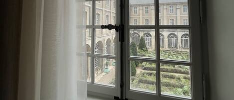 A window with a view of a building and a garden.