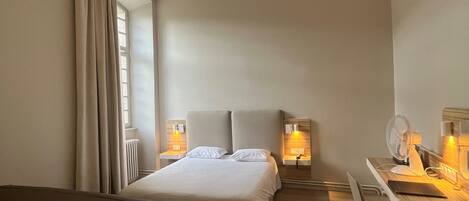 Una habitación de hotel con cama, escritorio, silla y sofá.