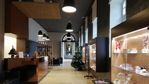 Un intérieur moderne avec un comptoir d’accueil, un sapin de Noël et des vitrines en verre où sont exposés divers objets.