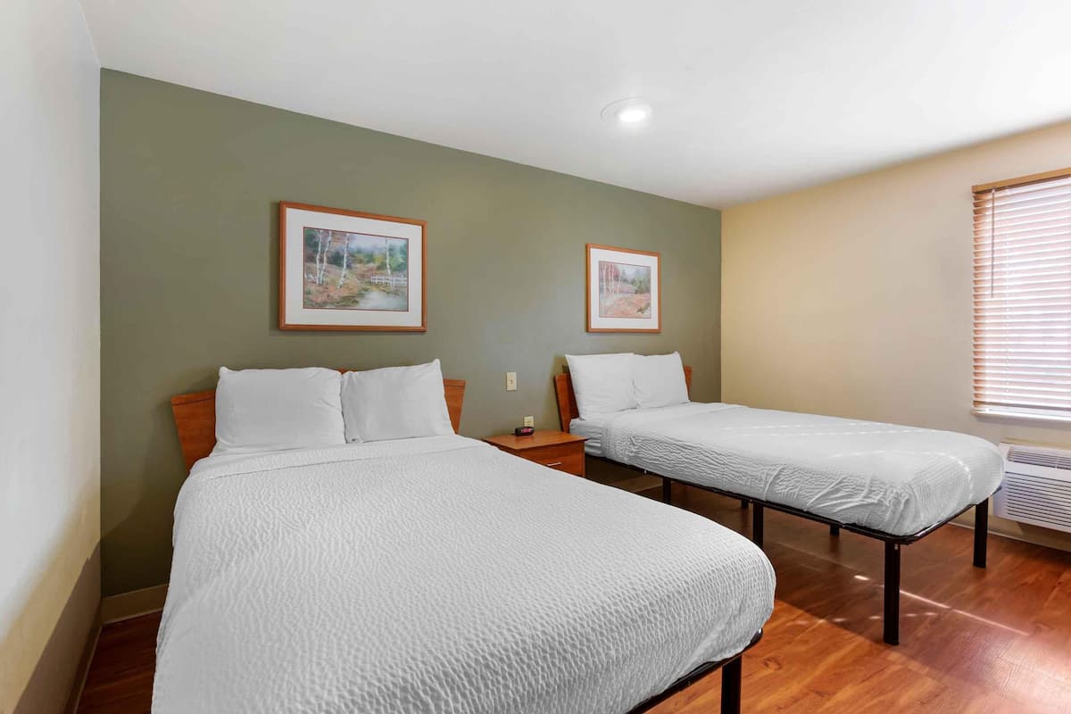 Two single beds with white bedding in a room with green walls and wooden flooring.