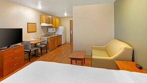 A compact hotel room with a bed, a TV, a small kitchenette, and a seating area. - Extended Stay America Select Suites - Phoenix - West (Phoenix)