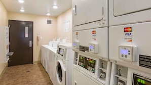 A laundry area with multiple washing machines and dryers, payment terminals for VISA and MasterCard, and a door with a security lock. - Extended Stay America Select Suites - Phoenix - West (Phoenix)