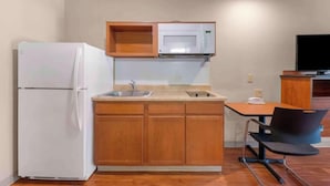 A compact kitchen with a refrigerator, microwave, sink, and wooden cabinets. - Studio 6 Extended Stay Birmingham Pelham  AL (Pelham)