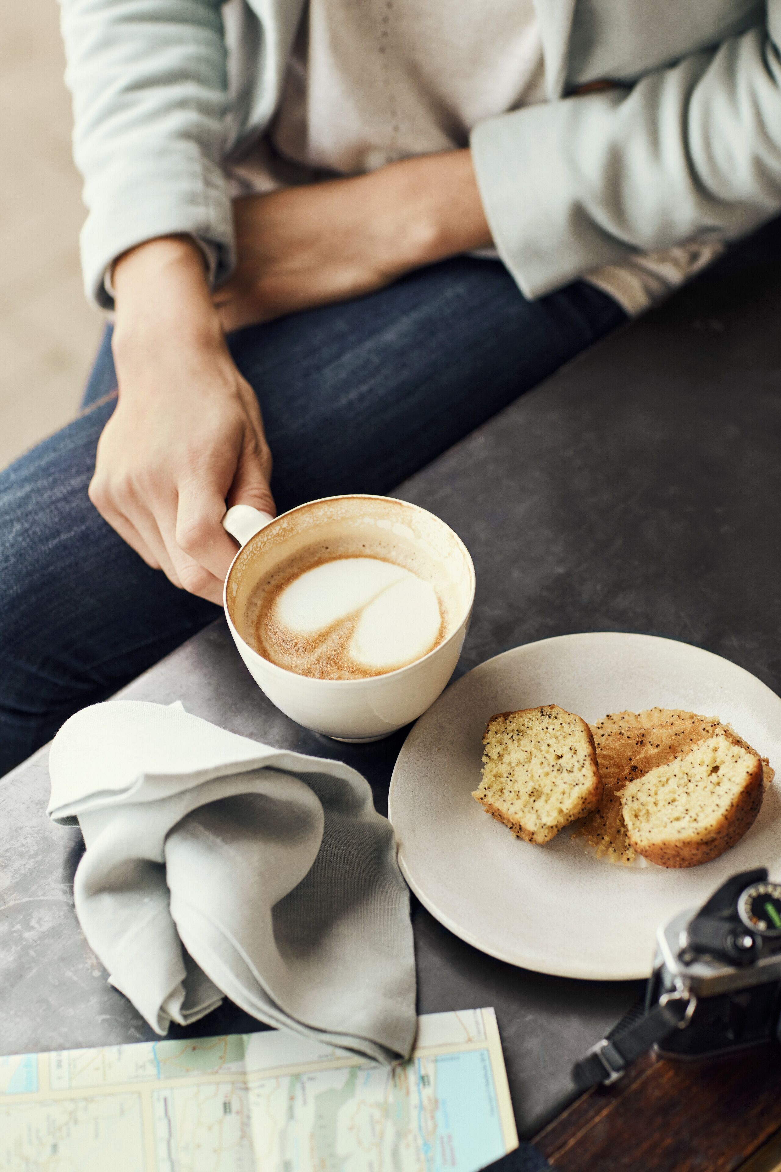 A person sitting with a cup of coffee and two slices of bread on a table.