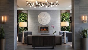 A modern lobby with a central seating area, a fireplace, and decorative wall plants. - The Westin Reston Heights (Reston)