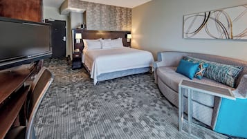 Ein Hotelzimmer mit einem großen Bett, einem Fernseher, einer Couch und einem kleinen Tisch.