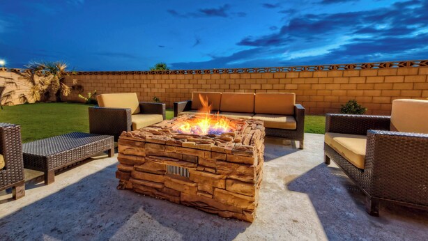 An outdoor patio with a stone fire pit, wicker furniture, and a brick wall. - Courtyard by Marriott Midland (Midland)