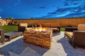 An outdoor patio with a stone fire pit, wicker furniture, and a brick wall. - Courtyard by Marriott Midland (Midland)