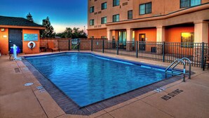 A swimming pool with a lifeguard station, a fenced area, and a building with multiple windows. - Courtyard by Marriott Midland (Midland)