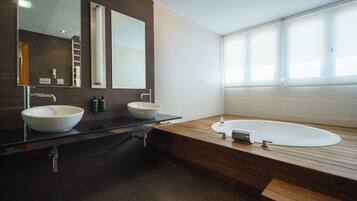 Un baño moderno con dos lavamanos, una bañera y un espejo grande.