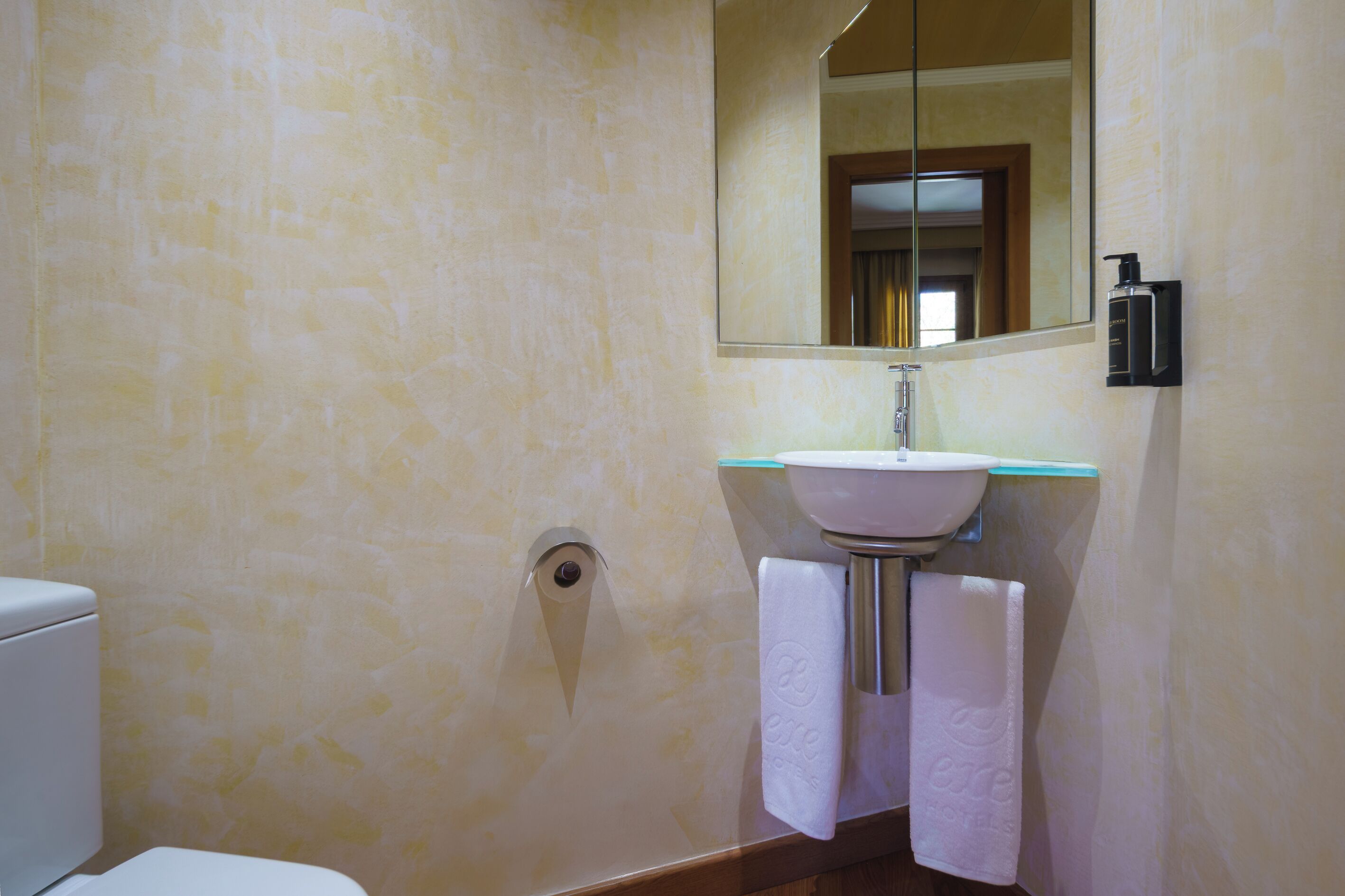 A bathroom with a toilet, sink, and mirror.