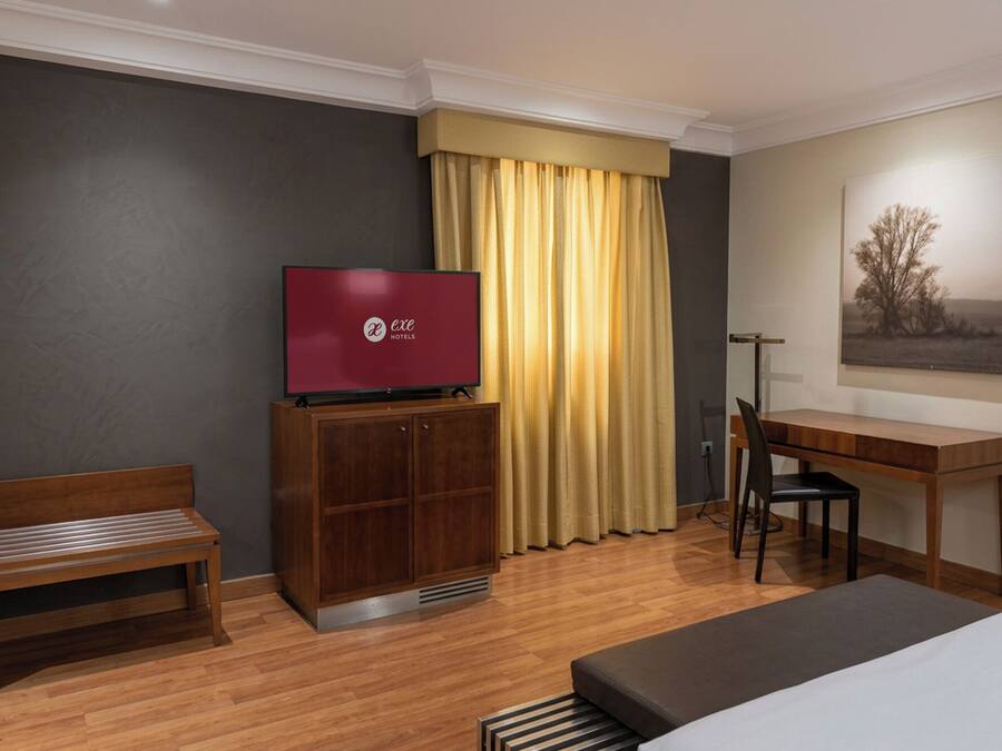 Ein Hotelzimmer mit Bett, Schreibtisch, Fernseher und Stuhl.