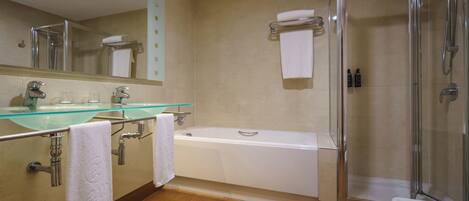 A modern bathroom with a glass-enclosed shower, a bathtub, and a glass-topped sink.