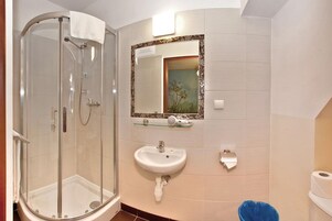 A bathroom with a glass-enclosed shower, a sink, a toilet, and a decorative mirror.