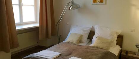 A bedroom with a bed, a bedside lamp, and a window with curtains.