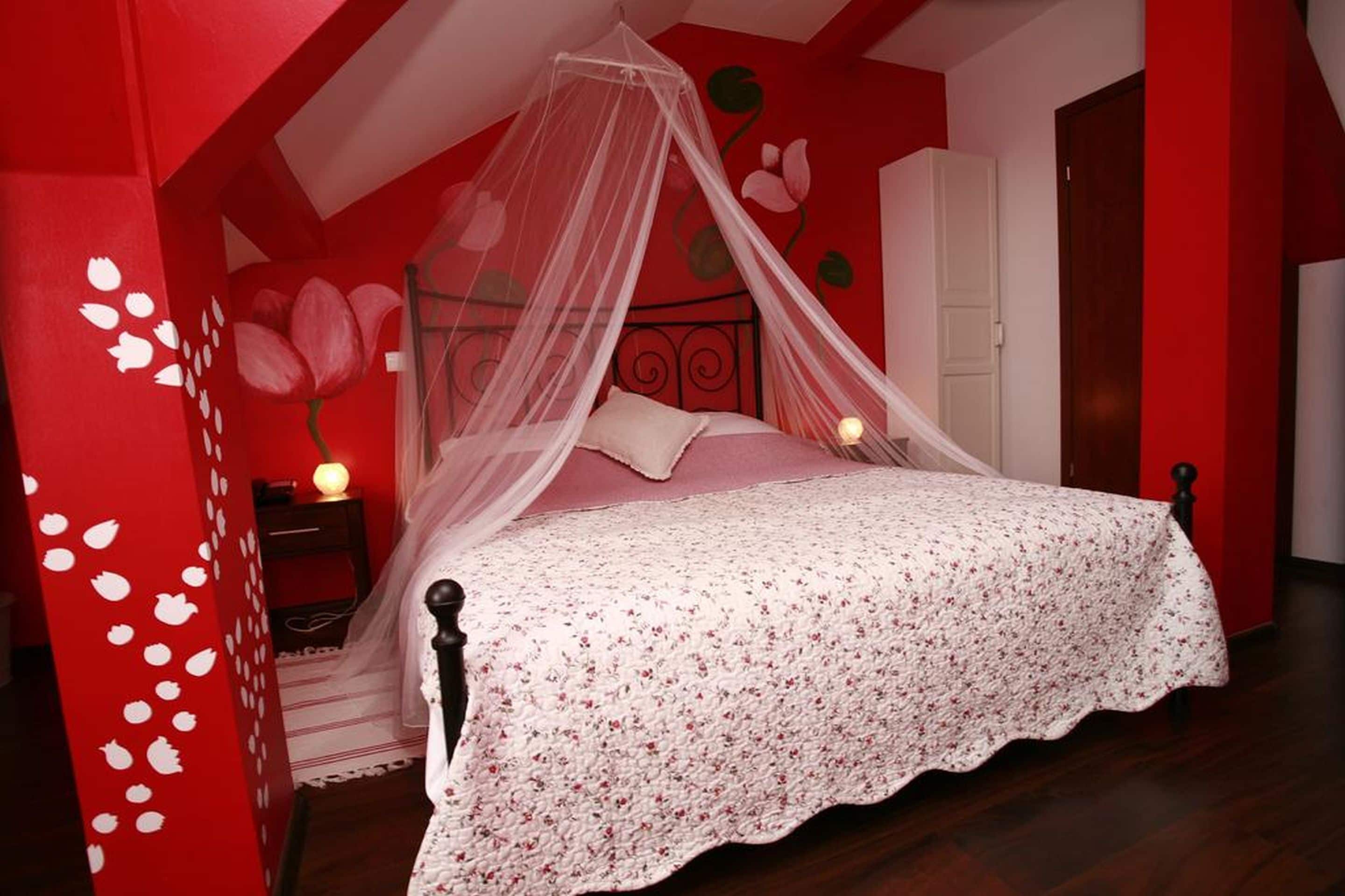 A bedroom with a four-poster bed, a nightstand, and a wall with floral decorations.