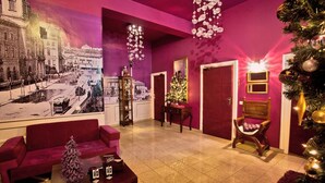 A lobby with a large black and white photo, a Christmas tree, a red sofa, and a wooden chair. - Castle Inn (Warsaw)