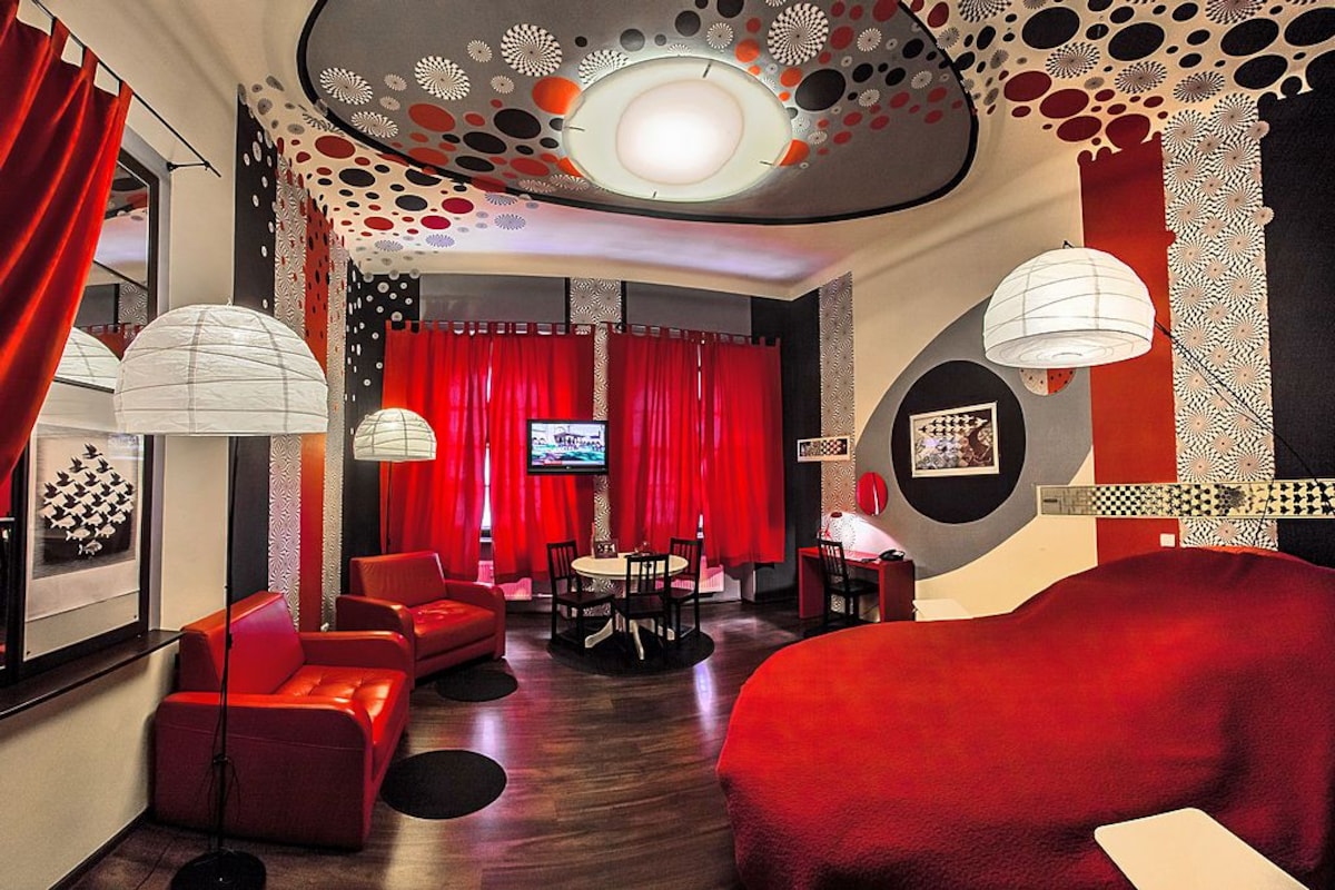 A modern interior with red furniture, a television, and patterned ceiling designs.