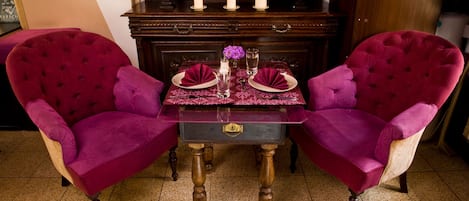 A dining table set with two chairs, a vase with flowers, and candles.