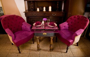 Un tavolo da pranzo apparecchiato con due sedie, un vaso con fiori e candele.