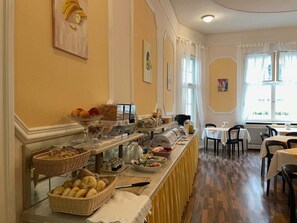 A breakfast buffet with various food items and a seating area with tables and chairs. - Hotel Castell (Berlin)