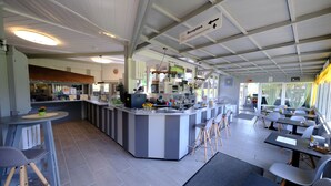 A modern restaurant with a reception area, a counter with bar stools, and a dining area with tables and chairs. - B+B Hotel Sonnenmatte Near Badeparadies (Titisee-Neustadt)