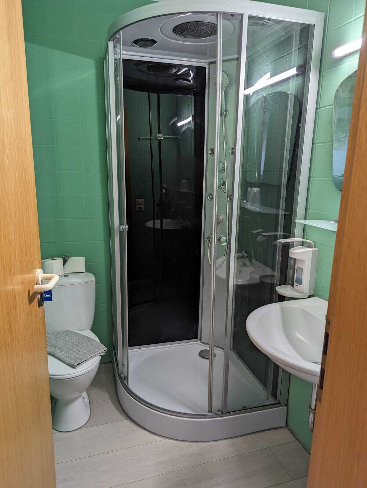 Une salle de bain avec une douche à parois de verre, un lavabo blanc et des toilettes.