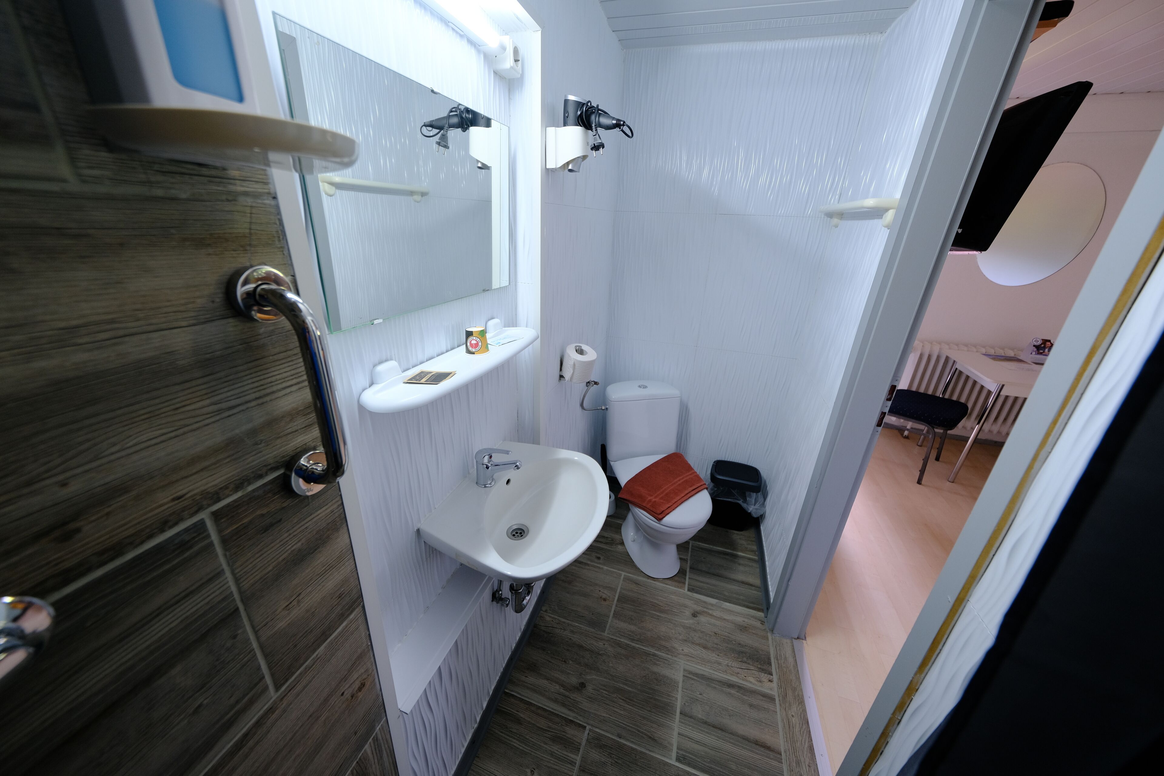 A compact bathroom with a white sink, a toilet, and a mirror.