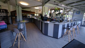 A bar area with stools, a counter, and a seating area with a table and chairs. - B+B Hotel Sonnenmatte Near Badeparadies (Titisee-Neustadt)