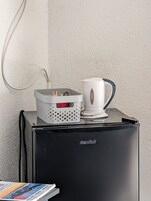 Un refrigerador Comee negro con una cafetera blanca y una cesta encima.