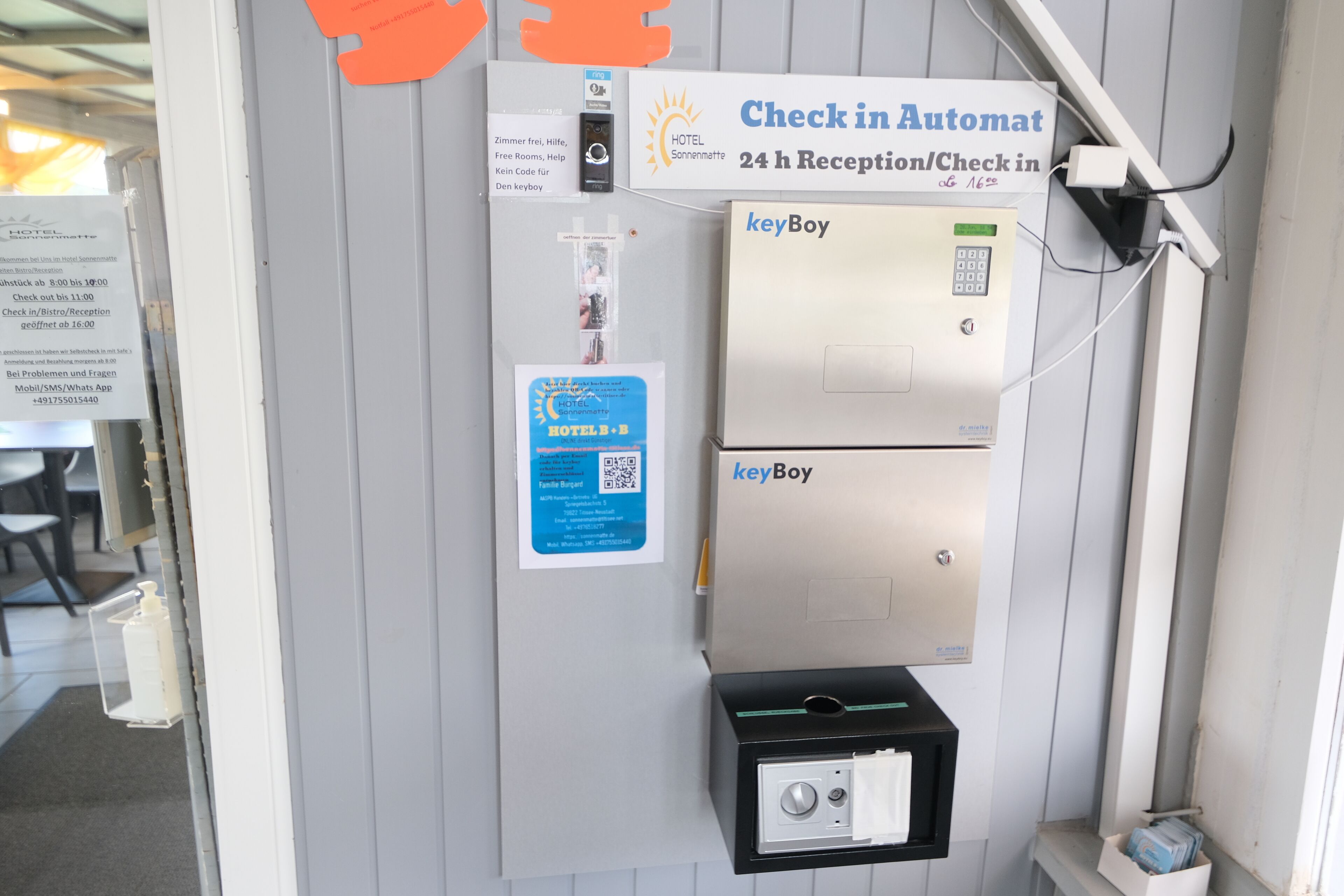 A hotel reception area with a check-in automat, a keyBoy device, and a QR code for hotel services.