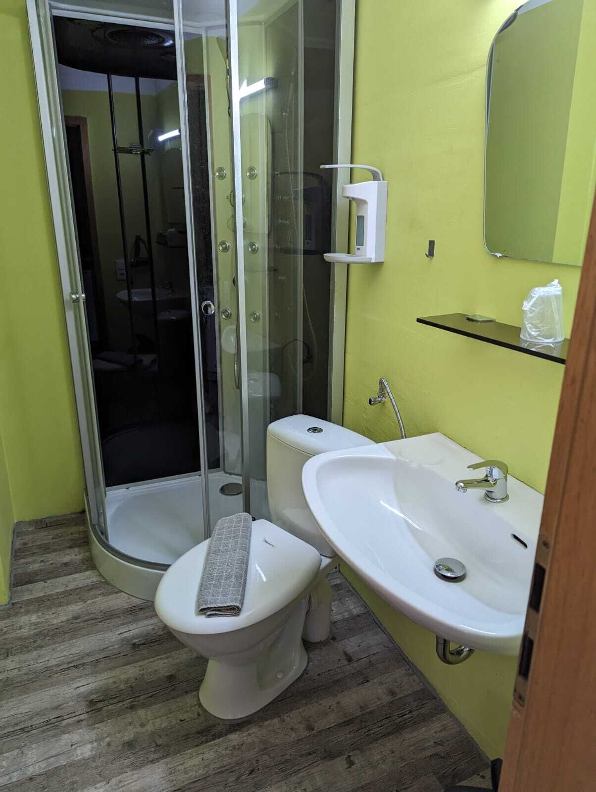 A bathroom with a glass-enclosed shower, a toilet, and two sinks.
