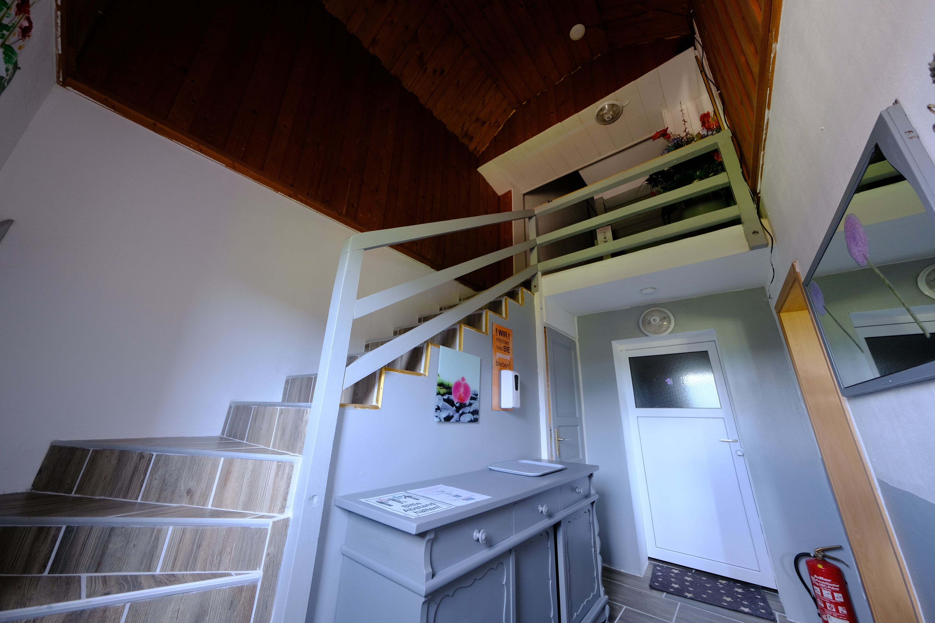 A staircase with a wooden finish, a white door, and a fire extinguisher mounted on the wall.