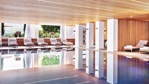 Un área de piscina interior moderna con sillones de descanso y techo de madera.
