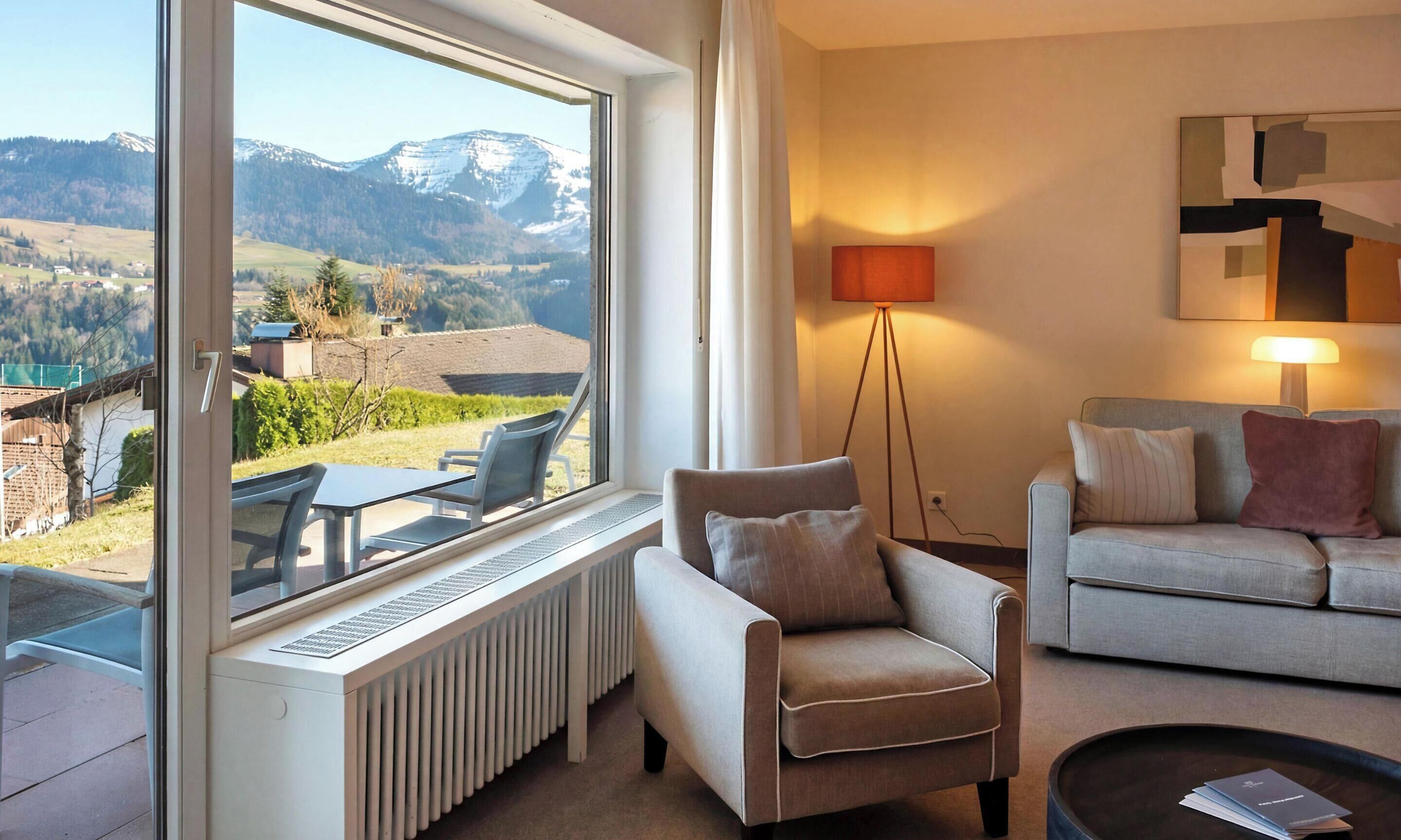 Ein Zimmer mit Bergblick, einem Heizkörper, einem Sofa, einem Sessel und einer Lampe.