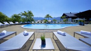 Zona de piscina con sillones de descanso y vistas a montañas.