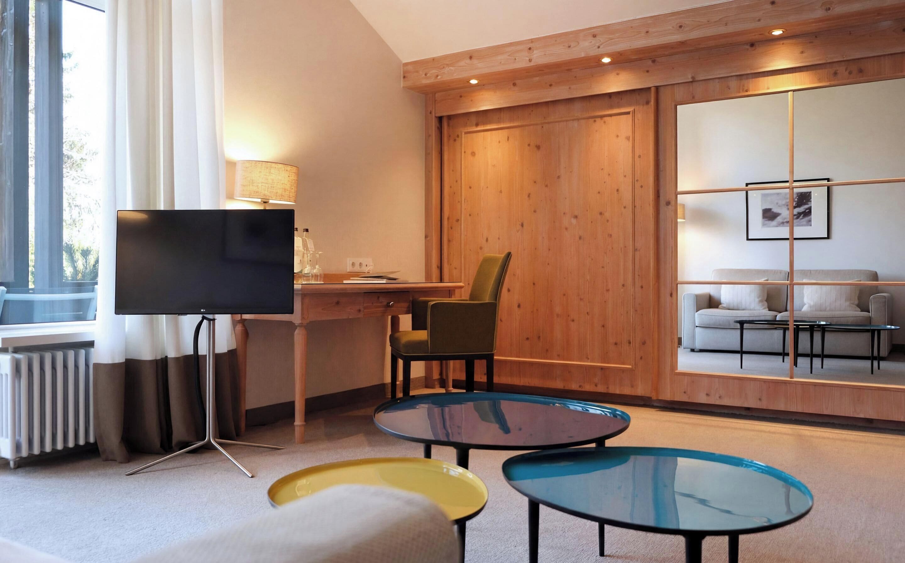 Un salon moderne comprenant un téléviseur, un bureau, une chaise et un canapé.