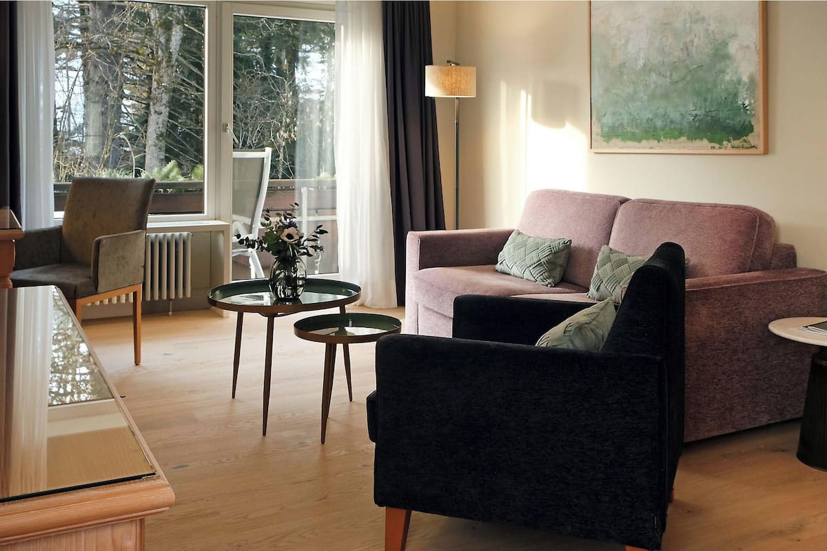 A living room with a sofa, armchair, coffee table, and a radiator.